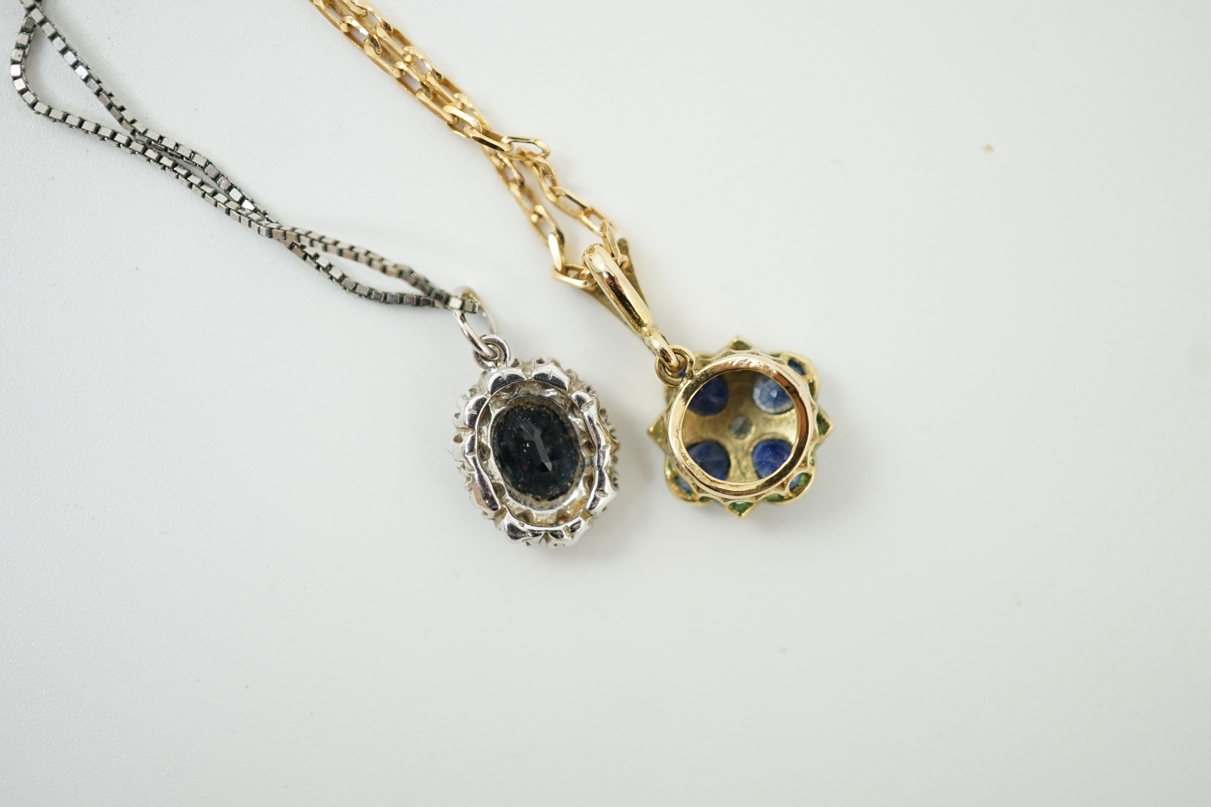 A modern 9ct gold, sapphire and diamond set pendant, overall 19mm, on a 375 chain, 38cm and a similar white metal, sapphire and diamond set pendant, on a 9ct white metal chain, gross weight 7 grams.